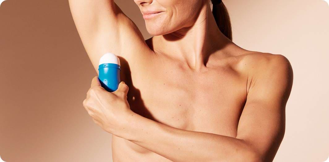 Vrouw brengt deodorant aan op haar oksel.