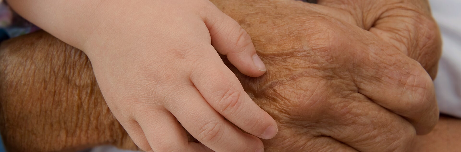 Een vrouw, gezien op haar rug, die haar schouder wast met een rijk schuim. Haar hand rust op de ingezeepte huid en de achtergrond is effen beige.