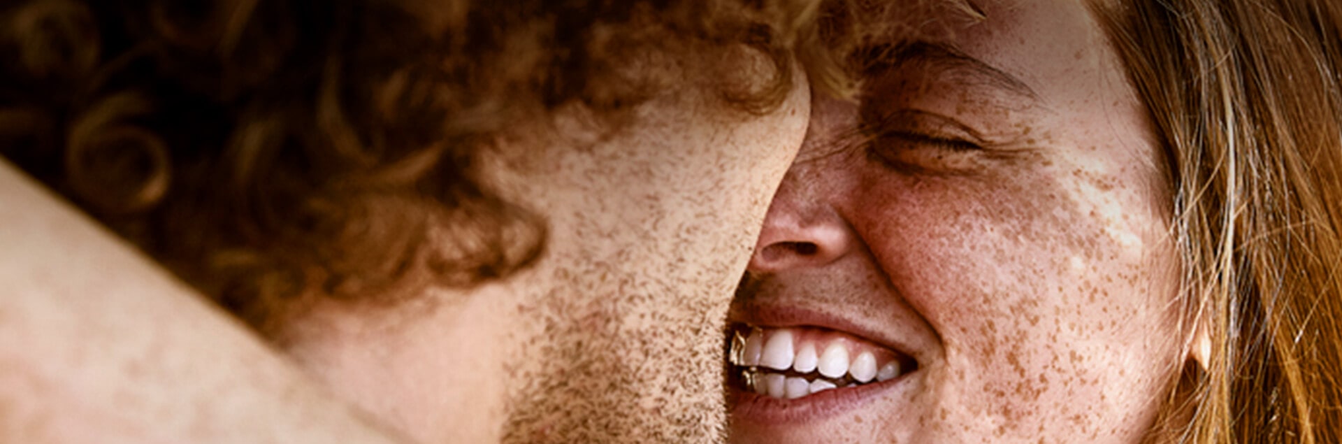 Een vrouw, gezien op haar rug, die haar schouder wast met een rijk schuim. Haar hand rust op de ingezeepte huid en de achtergrond is effen beige.